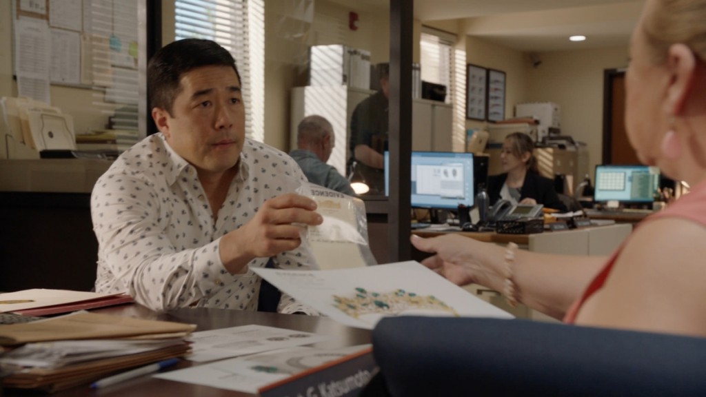 Le Lieutenant Gordon Katsumoto (Tim Kang) montre une pièce à conviction à Kumu (Amy Hill).