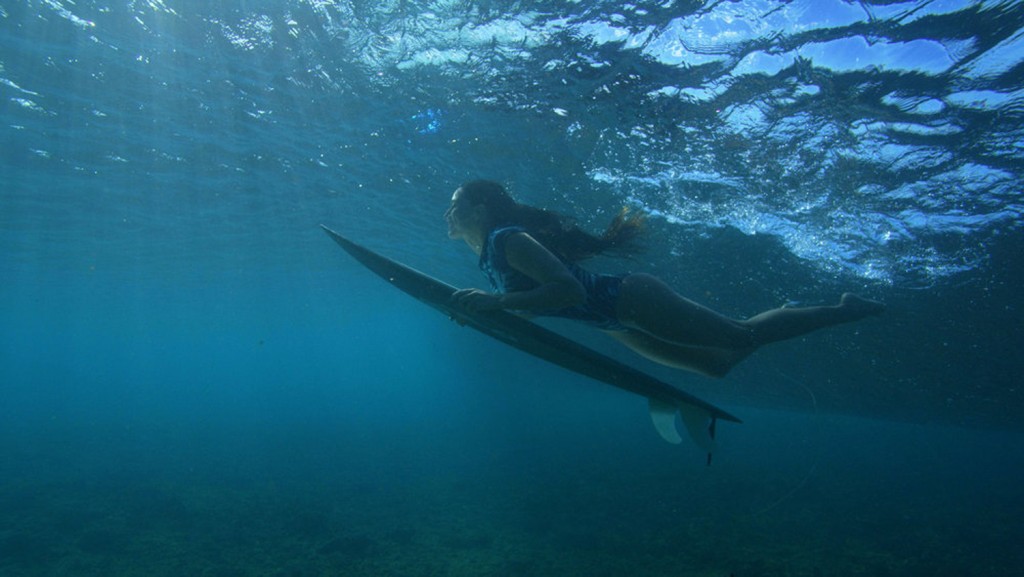 Malia Manuel sous l'eau avec sa planche de surf.